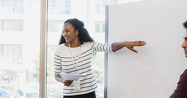 Woman standing pointing to a whiteboard