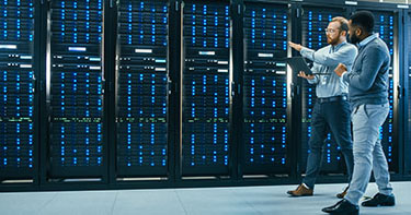 Two men walking in front of servers