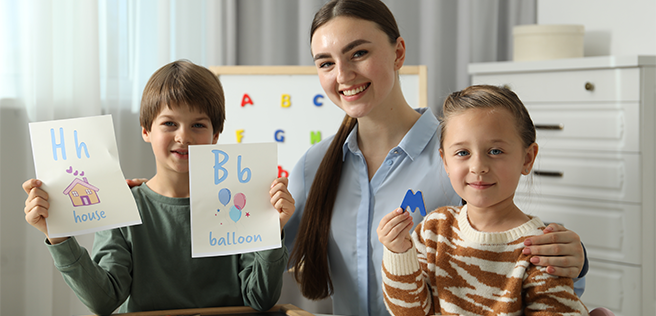 Teacher working on alphabet with a female and male student.