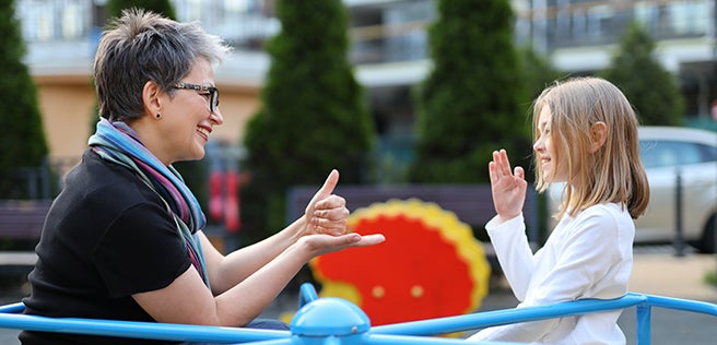 Women sitting with child practicing sign language