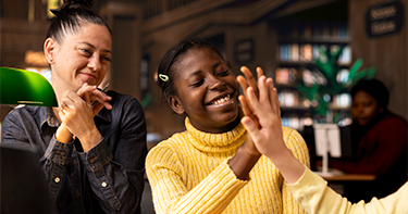 Girls sitting next to student high fiving.